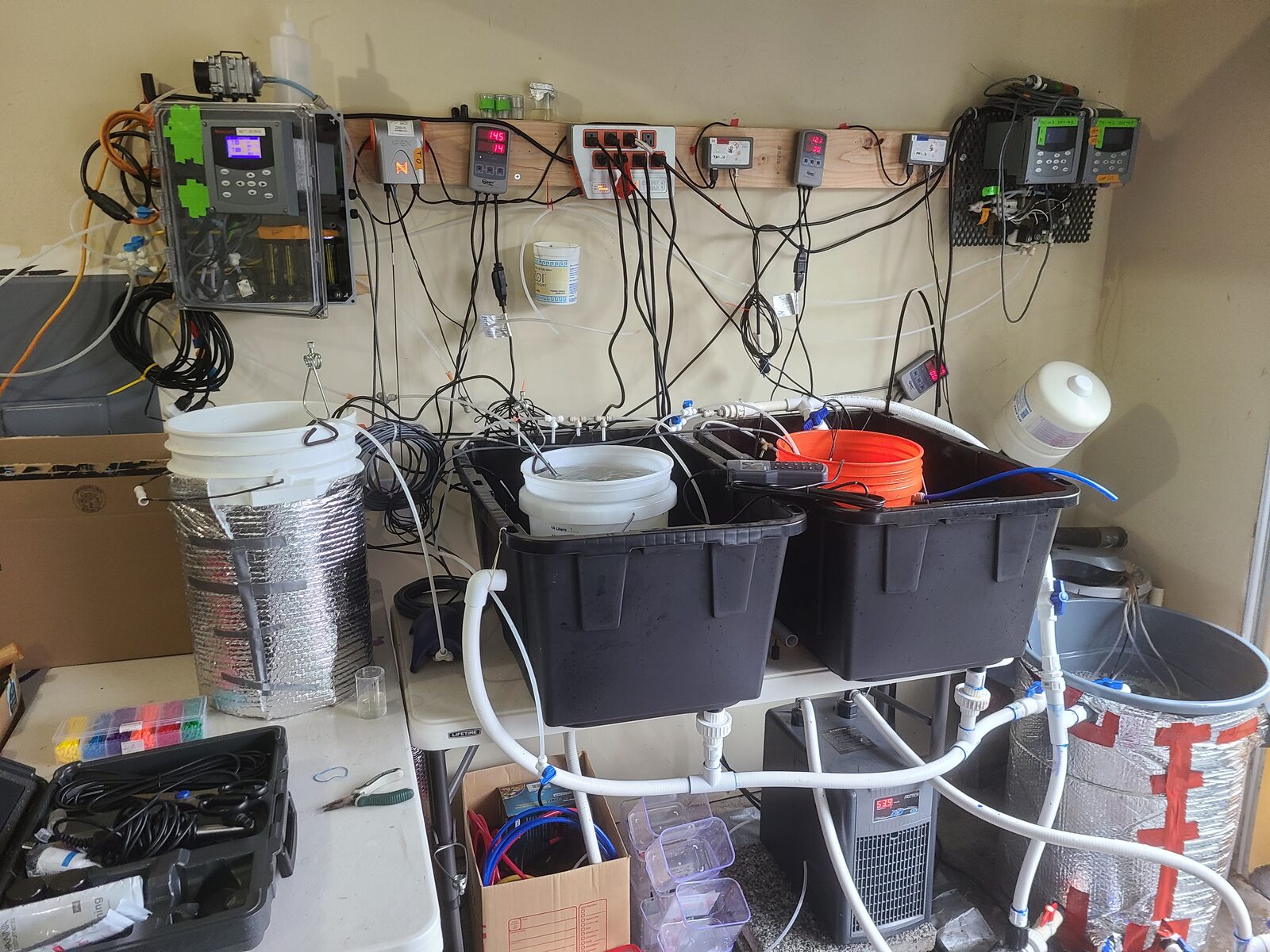 Laboratory bench with controllers, header buckets, tubing, and treatment tanks